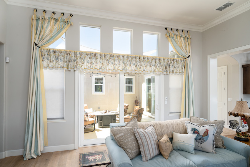 Living room with french doors, light blue couch, and floral patterned window treatments