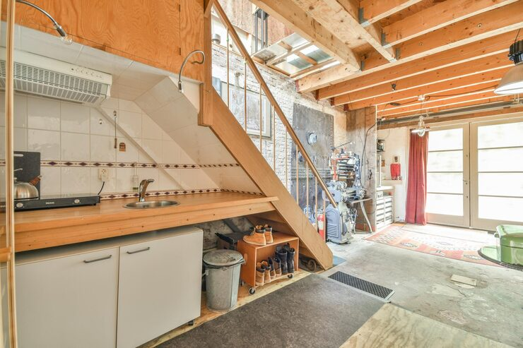 Worker installing wooden laminate flooring while kneeling on the floor in a modern room.