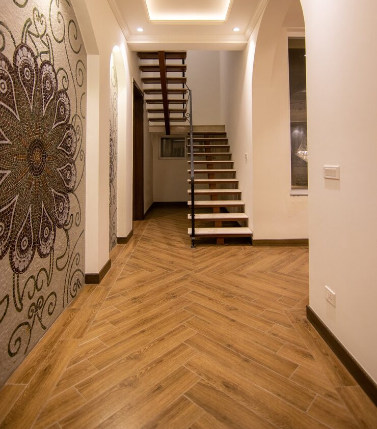 Modern living room interior with warm peach and white marble walls, an orange armchair, indoor green plants, and large windows allowing 
                       natural sunlight to fill the space.