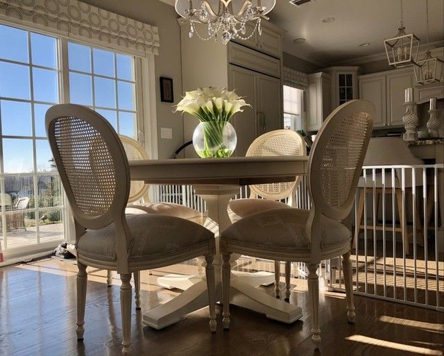 Traditional dining area with white pedestal table and cane-back chairs