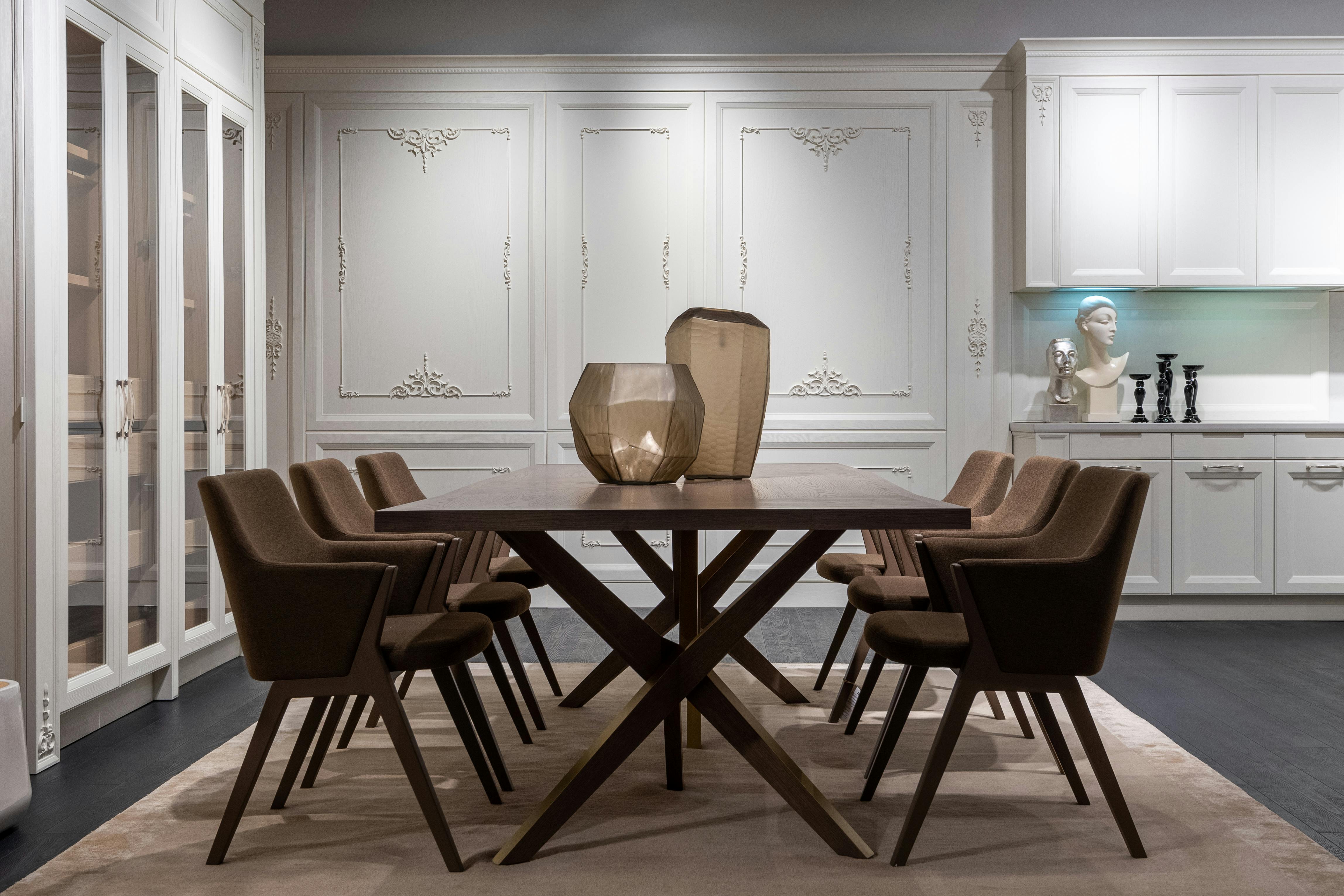 Luxury dining room with white ornate paneled walls, dark table, and brown chairs
