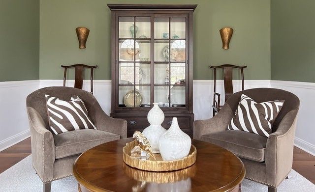 Sitting area with two velvet armchairs, round coffee table, and wood china cabinet
