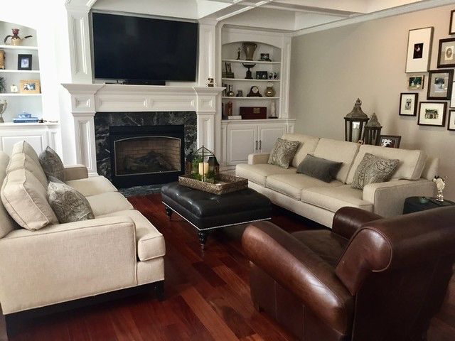 Traditional living room with fireplace, TV, cream couches, and leather armchair