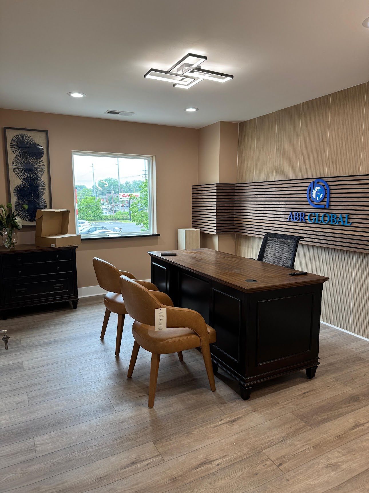 Modern office with dark wood desk, leather chairs, and ABR Global logo wall