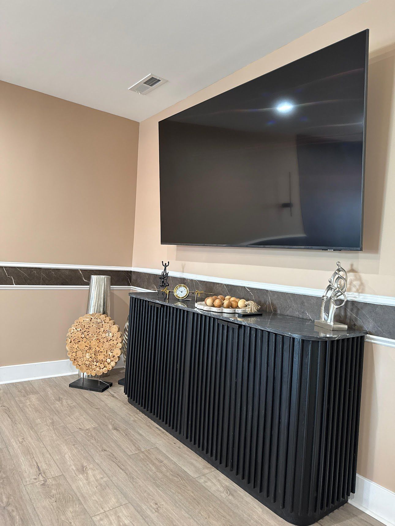Modern TV room with black fluted media console and large wall-mounted television