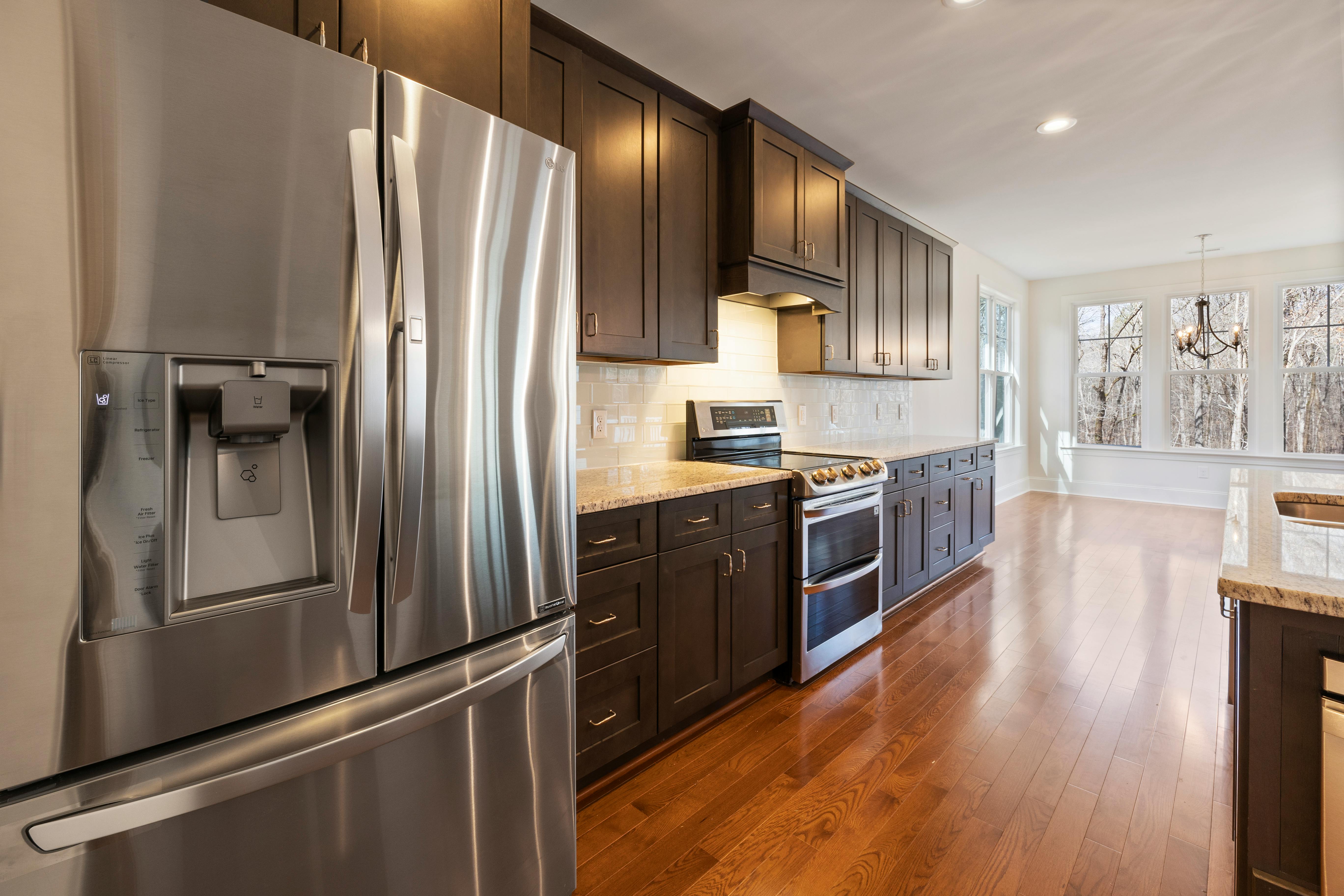 stainless steel refrigerator in modern kitchen with dark wood cabinets and hardwood floors