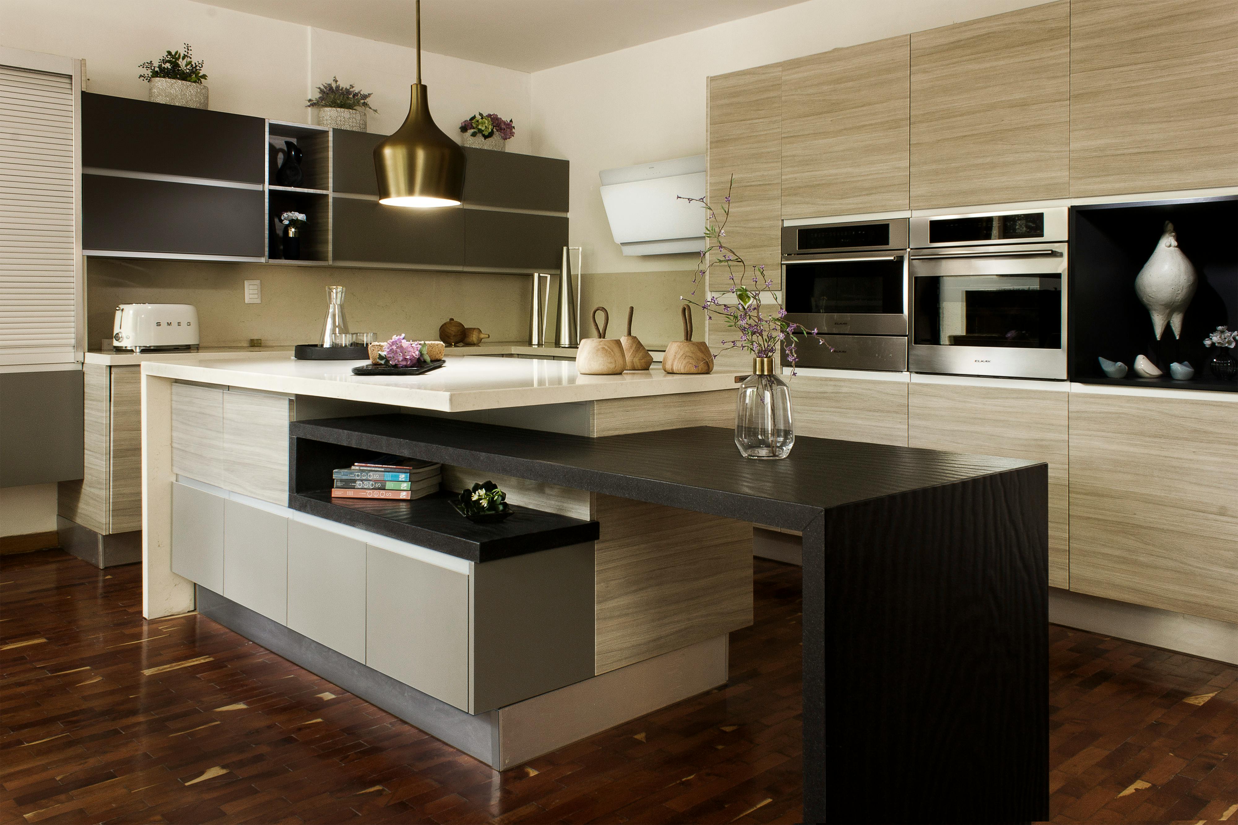 Modern kitchen with two-level island, light wood cabinetry, and built-in stainless steel ovens