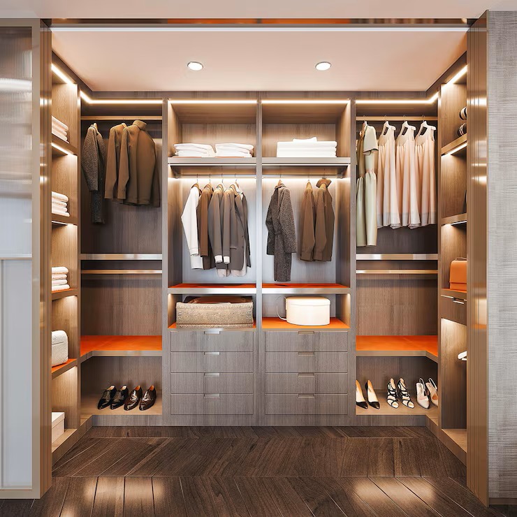 Luxury custom walk-in closet design with dark wood grain, integrated LED lighting, and striking orange accent shelves for clothes and shoe storage.