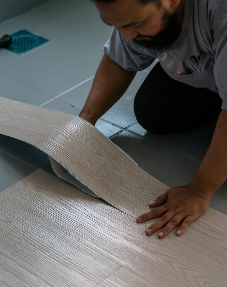 Modern living room interior with warm peach and white marble walls, an orange armchair, indoor green plants, and large windows allowing 
                       natural sunlight to fill the space.